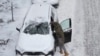 美国艾奥瓦州一名男子在清除汽车上的积雪。（2022年12月22日）