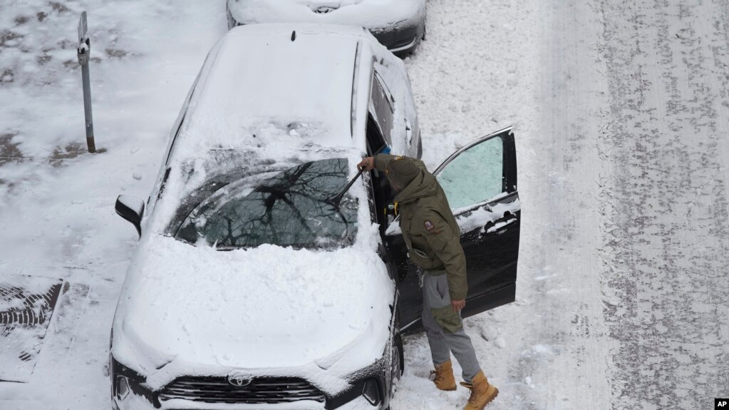 美国艾奥瓦州一名男子在清除汽车上的积雪。（2022年12月22日）(photo:VOA)