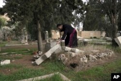 Hosam Naoum, seorang uskup Anglikan Palestina, menyentuh kuburan yang dirusak pengacau di Pemakaman Protestan bersejarah di Gunung Zion, Yerusalem, Rabu, 4 Januari 2023. (AP/ Mahmoud Illean)