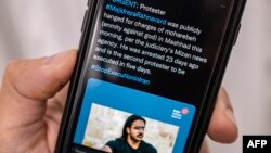 A person in the Cypriot capital Nicosia checks a mobile phone on December 12, 2022, displaying a Tweet about the execution announced by Iranian authorities of Majidreza Rahnavard, the second capital punishment linked to nearly three months of protests.