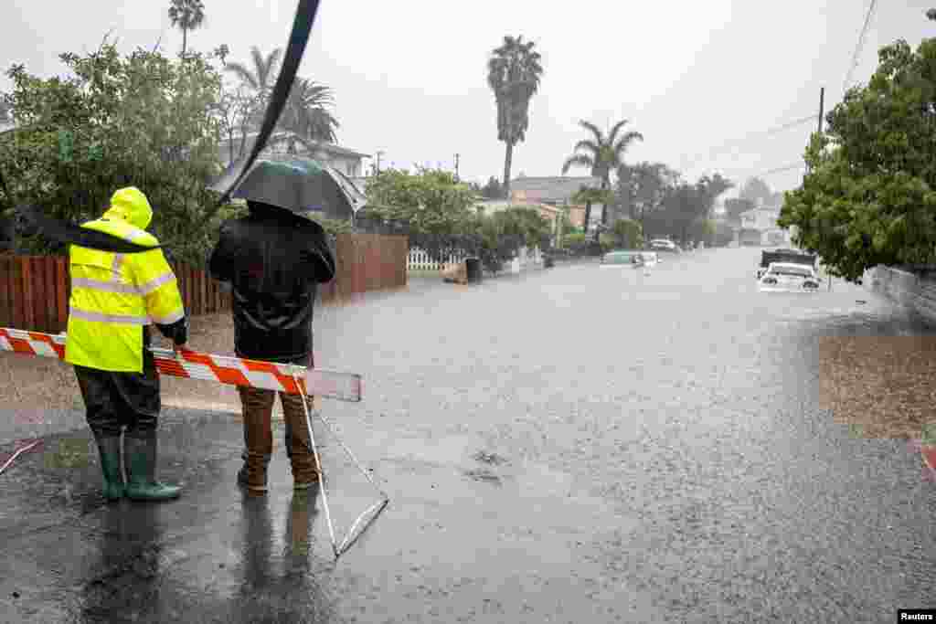 Residents look at abandoned cars on a flooded street in east Santa Barbara, Jan. 9, 2023.
