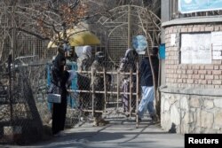 Seorang mahasiswi Afghanistan berdiri di depan gerbang masuk Universitas Kabul di Kabul, 21 Desember 2022. (REUTERS/Ali Khara)