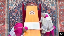 Pastor Georg Gaenswein (kiri), mencium peti mati Paus Emeritus Benediktus XVI saat misa pemakamannya di Lapangan Santo Petrus di Vatikan, Kamis, Januari 5, 2023. (Vatikan Media via AP)