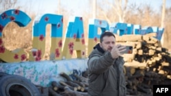 烏克蘭總統新聞局拍攝和公佈的照片顯示烏克蘭總統澤連斯基在訪問頓涅茨克前線地區時在斯拉夫揚斯克鎮的標誌前錄製對烏克蘭人民的視頻講話。(2022年12月6日)