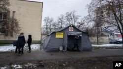 People stand in front of the heating tent "Point of Invincibility" in Kyiv, Ukraine, Nov. 28, 2022. 