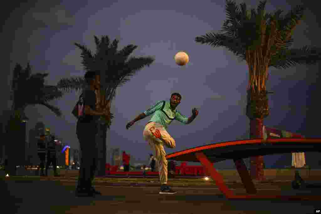 Hombres juegan con una pelota en el paseo marítimo Corniche en Doha, Qatar.