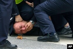Polisi menangkap dan menahan seorang pengunjuk rasa saat protes di sebuah jalan di Shanghai, China pada 27 November 2022. (Foto: AP)