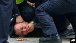 Policemen pin down and detain a protester during a protest on a street in Shanghai, China on Nov. 27, 2022.