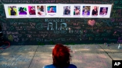 FILE - A person visits a makeshift memorial near the scene of a shooting targeting Black people at a supermarket, in Buffalo, on May 19, 2022.