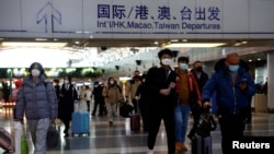 Wisatawan berjalan dengan barang bawaan mereka di Bandara Internasional Ibu Kota Beijing, di tengah wabah COVID-19 di Beijing, China 27 Desember 2022. (REUTERS/Tingshu Wang)