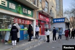 People wearing masks line up outside a pharmacy to buy products as coronavirus disease (COVID-19) outbreaks continue in Beijing, China December 6, 2022. REUTERS/Alessandro Diviggiano