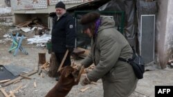 Oleksandr Sirenko, 65, looks at a woman greeting a dog as he cuts wood outside his house in the town of Siversk, Donetsk region, Ukraine, on Jan. 13, 2023, amid the Russian invasion of Ukraine.