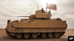 FILE - American soldiers drive a Bradley Fighting Vehicle during a joint exercise with Syrian Democratic Forces in northeastern Syria, Dec. 8, 2021. The U.S. will be sending Bradleys to aid Ukraine in its battle against Russian invaders.
