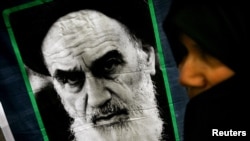 FILE - A woman passes a by picture of Ayatollah Ruhollah Khomeini outside Jamaran mosque in Tehran, Iran, June 3, 2005.