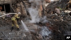 Firefighters extinguish a fire next to houses destroyed during a Russian attack in Kyiv, Ukraine, Dec. 31, 2022. 
