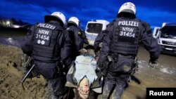 Para petugas kepolisian tampak membawa seorang demonstran yang memprotes perluasan wilayah tambang batu bara di Luetzerath, Jerman, pada 14 Januari 2023. (Foto: Reuters/Wolfgang Rattay)