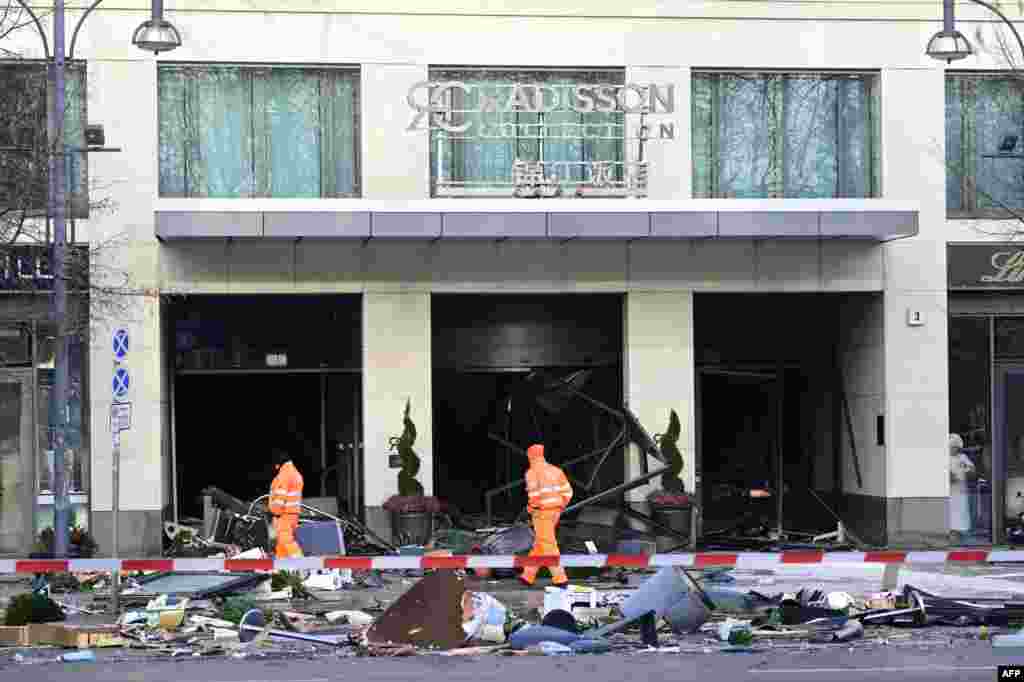 Pekerja kebersihan kota berjalan melewati puing-puing yang menutupi jalan di depan hotel Radisson Blu di Berlin setelah akuarium setinggi 14 meter di lobi hotel meledak, memaksa penutupan jalan di dekatnya.