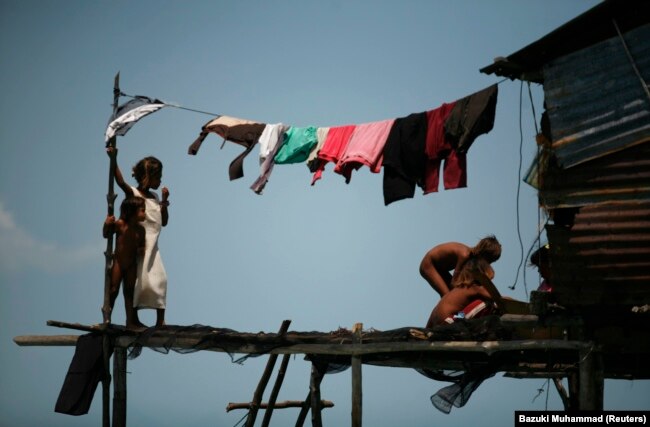 Seorang gadis Bajau Laut berjemur di perahunya di lingkungannya di Laut Sulawesi di negara bagian Sabah Malaysia, Kalimantan 17 Februari 2009. (Foto: REUTERS/Bazuki Muhammad)