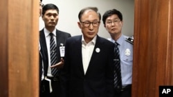 FILE - Former South Korean President Lee Myung-bak, center, appears for his first trial at Seoul Central District Court in Seoul, May 23, 2018. Myung-bak was eventually convicted of taking bribes worth millions of dollars.