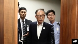 FILE - Former South Korean President Lee Myung-bak, center, appears for his first trial at the Seoul Central District Court in Seoul, May 23, 2018. Lee, who was sentenced to a 17-year prison term for a range of corruption crimes, received a presidential pardon, Dec. 27, 2022.