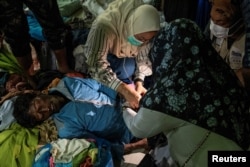 Indonesian medical officers look after a Rohingya refugee after their arrival at a temporary shelter in Pidie, Aceh province, Indonesia, December 26, 2022, in this photo taken by Antara Foto. (Antara Foto/Joni Saputra/via REUTERS)