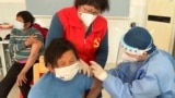 FILE - A medical worker administers a dose of a vaccine against COVID-19 to an elderly resident, during a government-organized visit to a vaccination center in Zhongmin village on the outskirts of Shanghai, Dec. 21, 2022. 