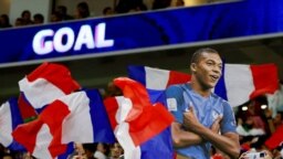 Potongan foto Kylian Mbappe dari Prancis diangkat tinggi-tinggi saat bendera Prancis dikibarkan oleh para penggemar selama pertandingan. (Foto: REUTERS/Bernadett Szabo)