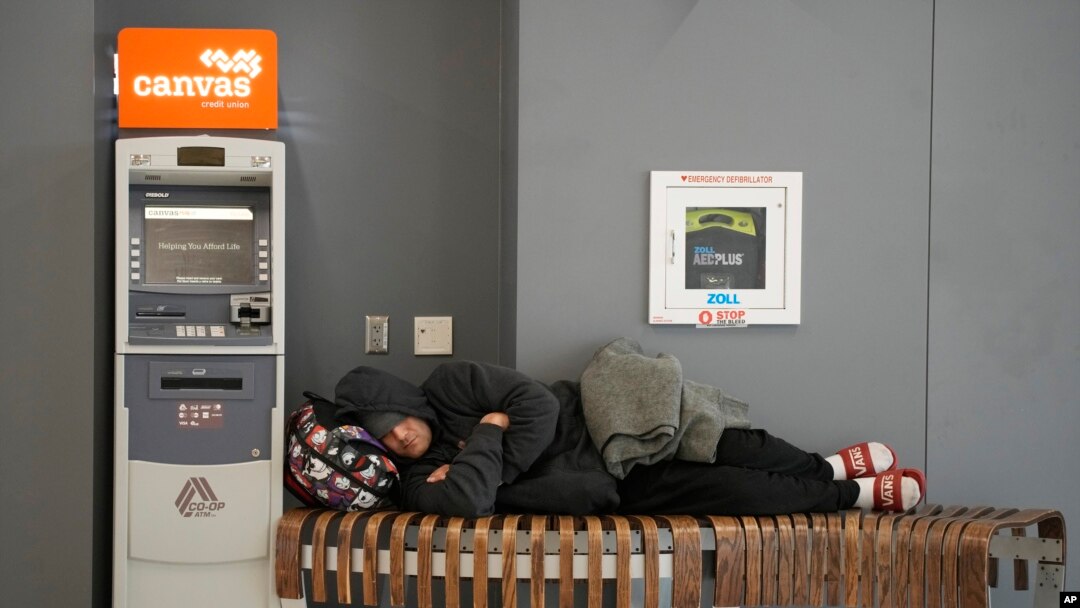 Putnik spava na klupi blizu mesta za prijem putnika aviokompanije Sautvest na međunarodnom aerodromu Denver, 27. decembar, 2022. (Foto AP/David Zalubowski)