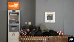 Putnik spava na klupi blizu mesta za prijem putnika aviokompanije Sautvest na međunarodnom aerodromu Denver, 27. decembar, 2022. (Foto AP/David Zalubowski)