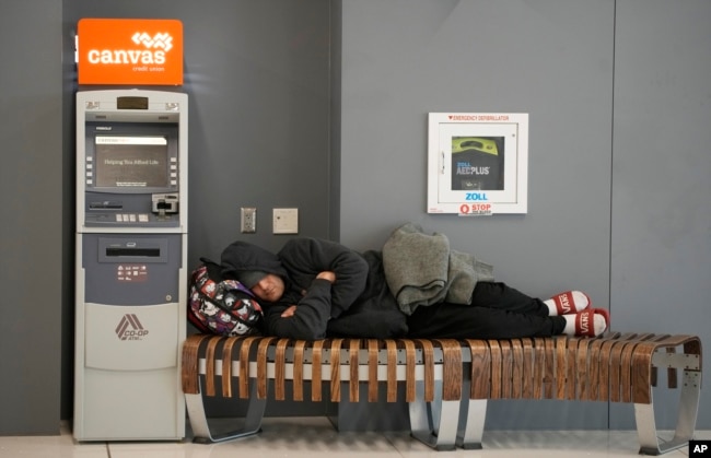 A traveler sleeps on a bench near the Southwest Airlines check-in counter at Denver International Airport, Dec. 27, 2022.