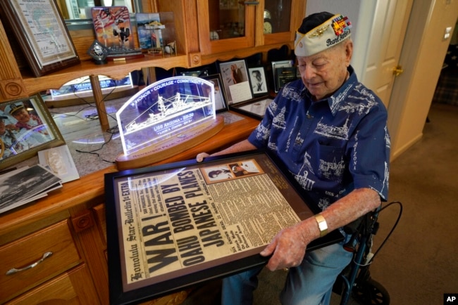 ARCHIVO - Lou Conter, sobreviviente de Pearl Harbor, de 102 años, sostiene una réplica enmarcada del Honolulu Star-Bulletin del 7 de diciembre de 1941 en su casa en Grass Valley, California, el 18 de noviembre de 2022.