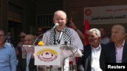 FILE - Noureddine Taboubi, secretary general of the Tunisian General Labour Union (UGTT) speaks to supporters of the union during a national public strike called by them, outside their headquarters in Tunis, June 16, 2022. 