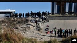 ARCHIVO - Decenas de migrantes esperan a subir a un autobús del gobierno estadounidense tras cruzar la frontera desde Ciudad Juárez, México, a El Paso, Texas, el 12 de diciembre de 2022. 