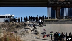 FILE - Migrants wait to get into a U.S. government bus after crossing the border from Ciudad Juarez, Mexico, to El Paso, Texas, Dec. 12, 2022. The mayor of El Paso declared a state of emergency, Dec. 17, 2022.