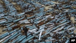 A war prosecutor observes collected parts of Russian rockets which were used to attack the city of Kharkiv, in Kharkiv, Ukraine, Dec. 22, 2022. 