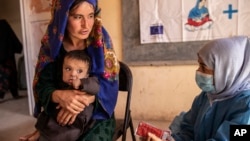 FILE - A Save the Children nutrition counselor, right, explains to a mother how to feed her 11-month-old daughter with therapeutic food used to treat severe acute malnutrition, in Sar-e-Pul province of Afghanistan, Sept. 29, 2022. (Save the Children via AP)