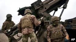 FILE - Ukrainian soldiers prepare to fire a self-propelled howitzer toward Russian positions near Avdiivka, Donetsk region, Ukraine, Dec. 26, 2022.