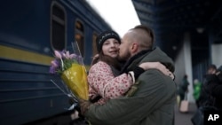 Ukrainian soldier Vasyl Khomko, 42, hugs his daughter Yana as she arrives at the train station in Kyiv, Dec. 31, 2022. 