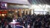 Para penumpang menunggu di bawah layar informasi yang menampilkan jadwal keberangkatan kereta di Stasiun Kings Cross, di tengah pemogokan para anggota serikat pekerja kereta api Inggris (RMT) di London. 