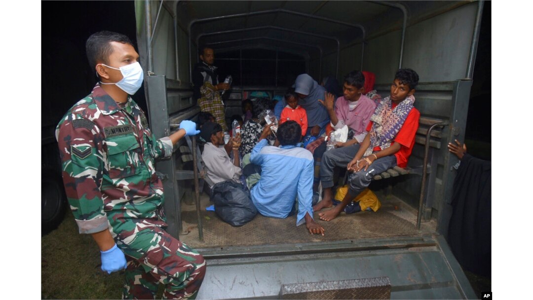 Etnis Rohingya duduk di belakang truk militer setibanya di tempat penampungan sementara setelah kapal mereka mendarat di Pidie, provinsi Aceh, 26 Desember 2022.