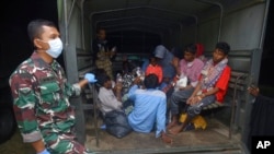 Ethnic Rohingya sit at the back of a military truck upon arrival at a temporary shelter after their boat landed in Pidie, Aceh province, Indonesia, Dec. 26, 2022.