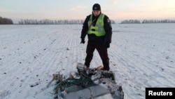 A police officer stands next to a part of a Russian cruise missile shot down by the Ukrainian Air Defense Forces, amid Russia's attack on Ukraine, in Kyiv region, Ukraine December 5, 2022.