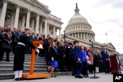 Logan Evans and Abigail Evans, children of the late U.S. Capitol Police Officer William "Billy" Evans, accompanied by their mother Shannon Terranova, speak their father's name during a ceremony marking the second anniversary of the violent insurrection by supporters of then-President Donald Trump, in Washington, Jan. 6, 2023.