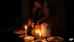 A woman prepares a meal by candle light at her home in Harare, Zimbabwe, Tuesday, Dec. 20, 2022. (Reuters)