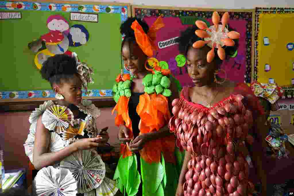 Jalokun Nifemi, left, wearing an outfit made from newspapers, Okpala Crystal, Center, wearing an outfit made from recycled plastic bags and Nathaniel Edegwa, right, wearing an outfit made from recycled plastic spoons, wait back stage before a &#39;trashion show&#39; in Sangotedo Lagos, Nigeria, Saturday, Nov. 19, 2022.