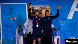 Lionel Messi holds out the trophy during the team's arrival in Buenos Aires, Dec. 20, 2022, after after winning the World Cup.