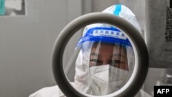 ২০২২ সালের ২৩ ডিসেম্বর সাংহাইয়ের জিং'আন জেলায় কোভিড-১৯ এর পরীক্ষা করার জন্য একজন স্বাস্থ্যকর্মী সোয়াব নমুনা নেওয়ার জন্য অপেক্ষা করছেন।