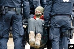 Police officers carry away a protester at the village Luetzerath near Erkelenz, Germany, Jan. 12, 2023.