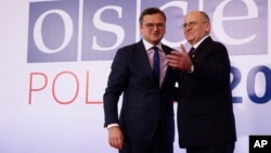 Polish Minister of Foreign Affairs Zbigniew Rau, right, welcomes his Ukrainian counterpart Dmytro Kuleba, left, during a high-level meeting of the Organization for Security and Cooperation in Europe in Lodz, Poland, Dec. 1, 2022.