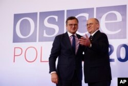 Polish Minister of Foreign Affairs Zbigniew Rau, right, welcomes his Ukrainian counterpart Dmytro Kuleba, left, during a high-level meeting of the Organization for Security and Cooperation in Europe in Lodz, Poland, Dec. 1, 2022.